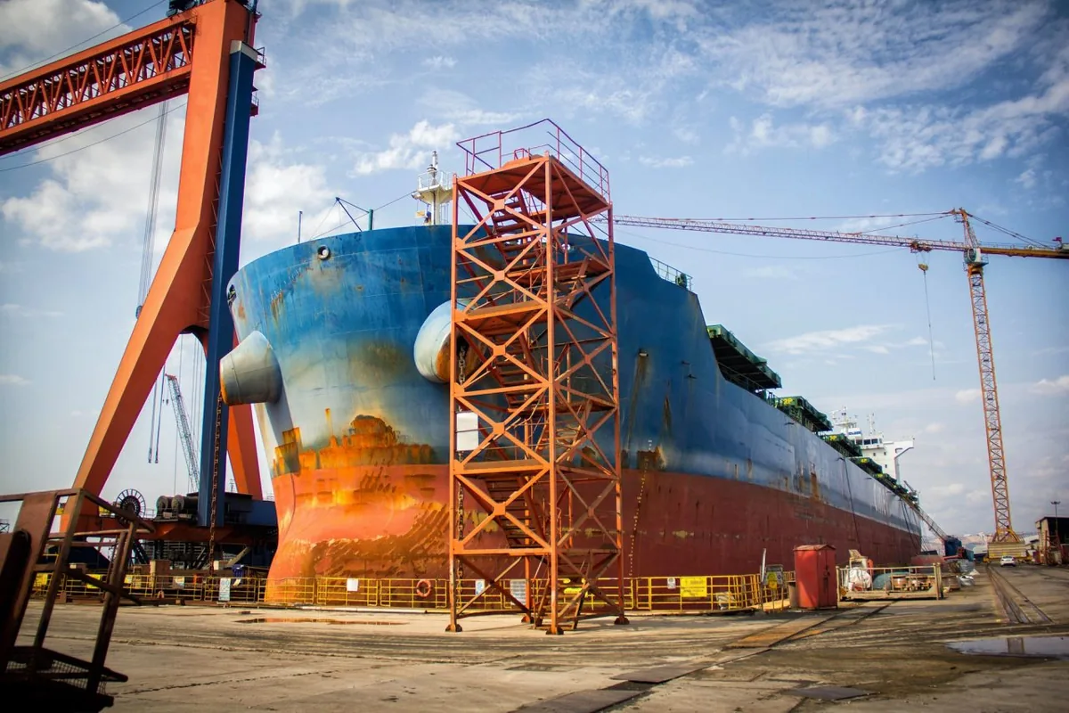 Container ship in a shipyard beside loading cranes